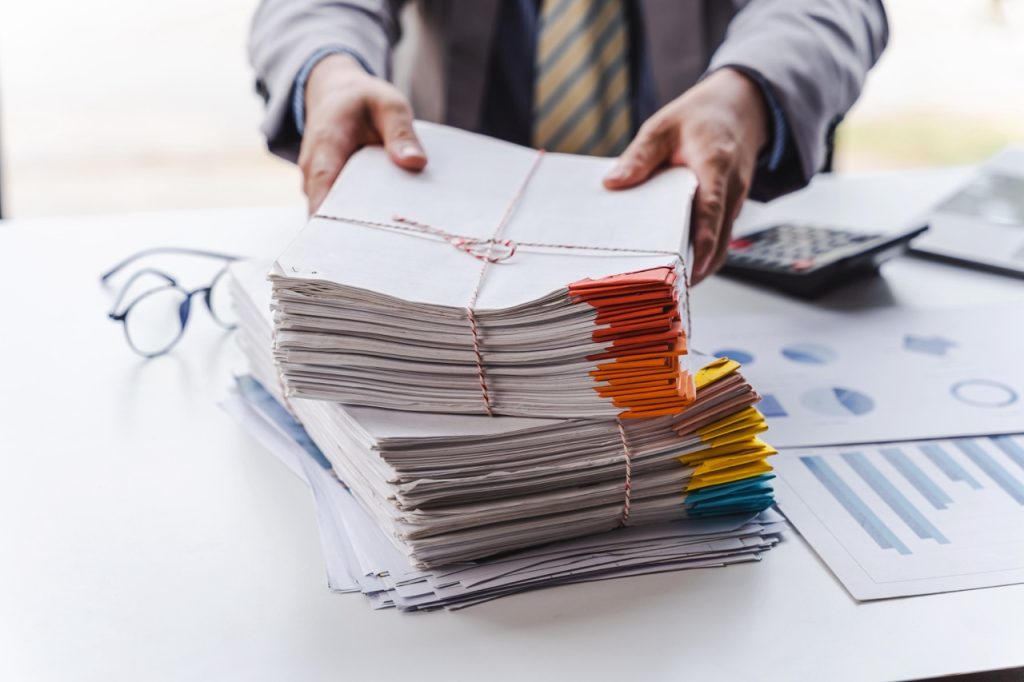 Stack of documents, pile of papers on office desk employee’s table, closeup, Asian people.